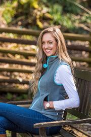 smiling model sitting on bench wearing ladies grey fleece gilet with sky blue trim