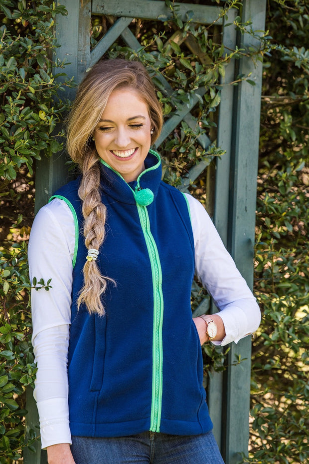 Model smiling in garden wearing Nattily dressed navy fleece gilet with bright green trim