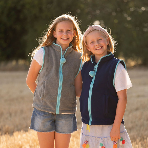 two girls modelling grey and navy fleece gilets with sky blue trim